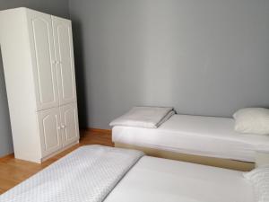 two beds in a room with white walls and wooden floors at Apartmants Mazoljice in Mostar