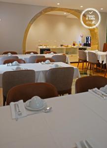 una sala da pranzo con tavoli e sedie bianchi di Casa dos Ofícios Hotel a Tomar