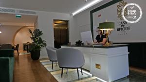 a woman sitting at a counter in a lobby at Casa dos Ofícios Hotel in Tomar