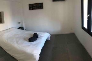 una camera da letto con un letto bianco con un oggetto nero sopra di Charmante maison à 5min de Marcoule a Codolet