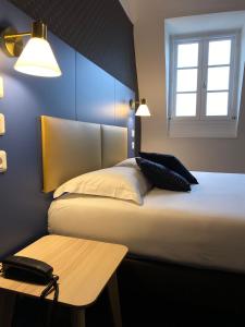 a bedroom with a bed with a table and a window at Hotel Colbert in Tours