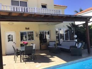 a patio with a table and chairs next to a pool at Carolyn Villa is a Luxury 4-Bedroom Villa with Private Pool in Ayia Napa in Ayia Napa
