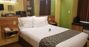 a hotel room with a bed and a phone at Microtel Inn & Suites by Wyndham Delphos in Delphos