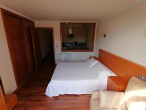 een slaapkamer met een wit bed en een bank bij Apartamentos Ay Sálvora in O Grove