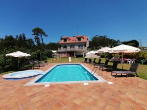 a swimming pool with chairs and a house in the background at Apartamentos Ay Sálvora in O Grove