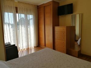 a bedroom with a bed and a dresser and a television at Apartamentos Ay Sálvora in O Grove
