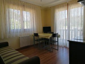 a living room with a table and chairs and windows at Apartamentos Ay Sálvora in O Grove