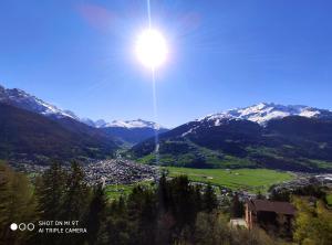 a sun shining over a valley with snow covered mountains at Residence Mirage in Oga