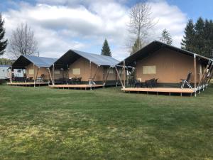 Montenau的住宿－Camping Oos Heem，田野里一排配有桌椅的帐篷