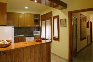 a kitchen with wooden cabinets and a counter top at Casa Rural Cal Met in Sant Boi de Lluçanès