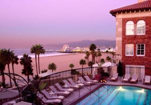 a hotel with a pool and chairs and the beach at Casa Del Mar in Los Angeles