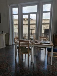 una sala da pranzo con tavolo, sedie e finestre di Ace Rooms VSG a Villa San Giovanni