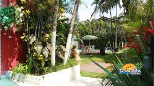 a garden with palm trees and a house at Pousada Dolce Vita in Itanhaém