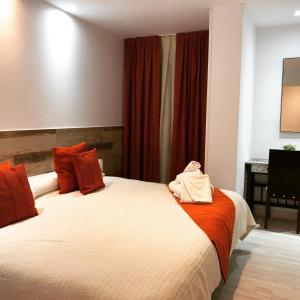 1 dormitorio con 2 camas, cortinas rojas y escritorio en Hotel tres estrellas Casa Maribona Gela en El Puente