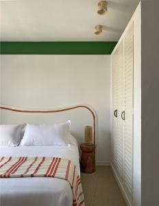 a bedroom with a white bed with a green headboard at Hôtel Le Sud in Juan-les-Pins