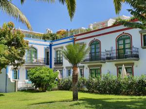 un bâtiment avec un palmier en face dans l'établissement Billy's Puerto de Mogán Apartments by LIVVO, à Puerto de Mogán