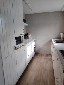 a kitchen with white cabinets and a sink and a stove at Louisiana 1 - Koninklijke Baan 71-B1 in De Haan