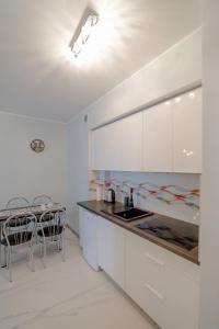 a kitchen with white cabinets and a table with chairs at Apartament Thomas 2 in Świnoujście