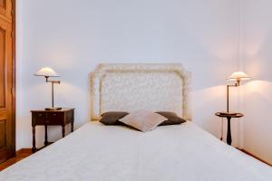 een slaapkamer met een groot wit bed met 2 lampen bij Mango Apartment - Faro city center in Faro