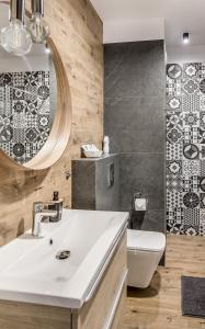 a bathroom with a sink and a toilet and a mirror at PREMIUM Apartments New Town Private Parking Included in Szczecin