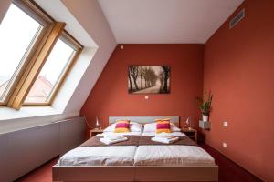 a bedroom with a bed with orange walls and windows at Ruby Blue in Ostrava