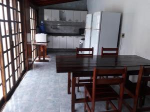 cocina con mesa de madera y nevera en MARAVILHOSA CASA COM PISCINA E AR CONDICIONADO - até 10 PESSOAS em MARESIAS SÃO SEBASTIÃO en São Sebastião