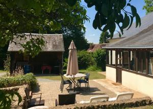 een parasol en stoelen en een tafel in de tuin bij Gite Le Bois aux Moines in Lavaré