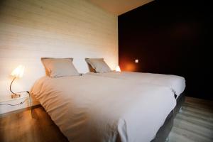 een groot wit bed in een kamer met een lamp bij Gite Le Bois aux Moines in Lavaré