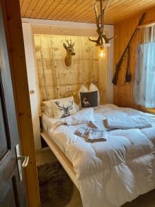 Dormitorio con cama blanca y cabeza de ciervo en la pared en Chalet Ariane, en Blatten bei Naters