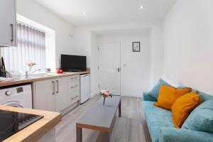 a living room with a blue couch and a kitchen at Smart Apartment Close2City in Leicester