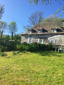 an old stone house with an umbrella in a yard at Maison confortable avec vue sur la montagne à Le Fau in Le Fau
