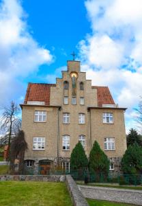 ein großes Backsteingebäude mit einem Kreuz oben in der Unterkunft DOMUS MARIAE Gietrzwałd in Gietrzwałd