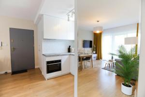 Una cocina con gabinetes blancos y una sala de estar. en M&K Apartament Moc Natury Sobieszewo - Wyspa Sobieszewska, en Gdansk