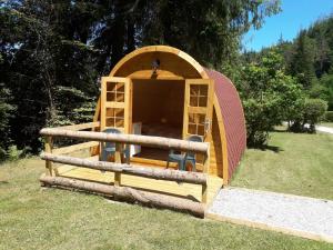 uma casa de iguanas de madeira com cadeiras na relva em La Pointe Camping em Châteaulin
