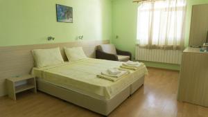 a bedroom with a bed and a chair in it at Guest House Gardeli in Tsarevo