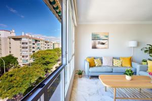 een woonkamer met een bank en een groot raam bij Apartamento Málaga City Beach in Málaga