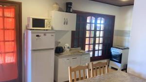 a kitchen with a white refrigerator and a microwave at Cabañas Marcelo in Barra del Chuy