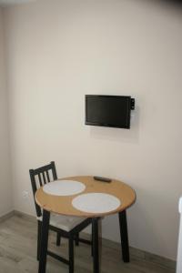 a wooden table with two chairs and a tv on a wall at Alka in Mielno