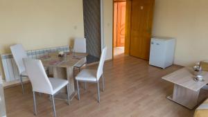 a dining room with a table and white chairs at Guest House Gardeli in Tsarevo +10 photos