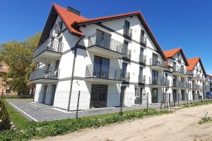 ein weißes Gebäude mit orangefarbenem Dach in der Unterkunft Apart Family in Łeba