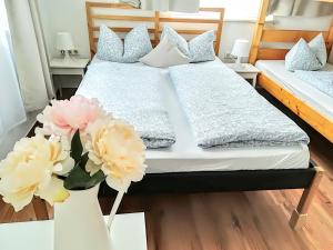 a bedroom with two beds and flowers on a table at House LA Neuschwanstein Blick in Füssen