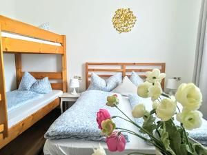 House LA Neuschwanstein Blick في فوسن: غرفة نوم بسريرين و مزهرية بها ورد