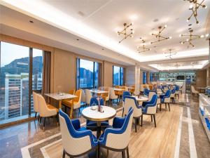 a restaurant with tables and chairs and windows at Kyriad Marvelous Hotel Guiyang Future Ark in Guiyang