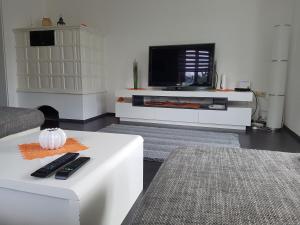 ein Wohnzimmer mit einem TV und einem weißen Tisch in der Unterkunft Green Hill Apartments - Feldkirch in Feldkirch