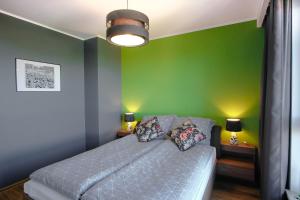 - une chambre avec des murs verts et un lit avec des oreillers dans l'établissement SUNRISE HOME w sercu Gdańska, à Gdańsk