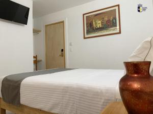 a bedroom with a bed and a vase on a table at Hotel Real GDL in Guadalajara
