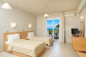 a hotel room with two beds and a television at Kohylia by La Scala Beach in Limenas
