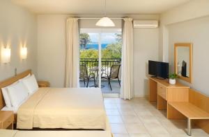 a bedroom with a bed and a television and a balcony at Kohylia by La Scala Beach in Limenas