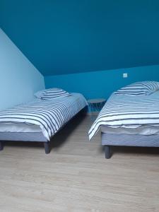 two beds in a room with a blue wall at La petite maison in Bracquemont