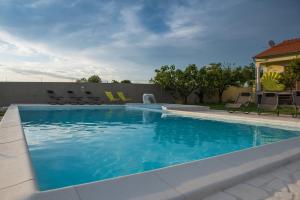 a swimming pool with blue water in a yard at Dubis House in Zadar